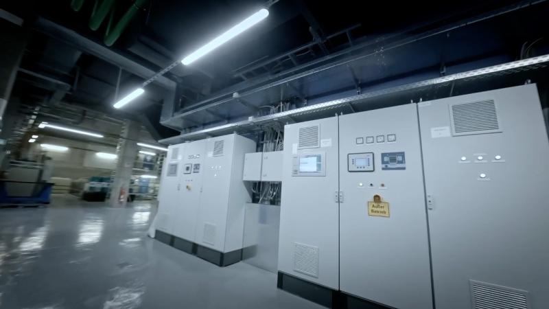 Innenraum eines Heizkraftwerks mit großen Steuerungsschränken, Anzeigen und Industriebeleuchtung.