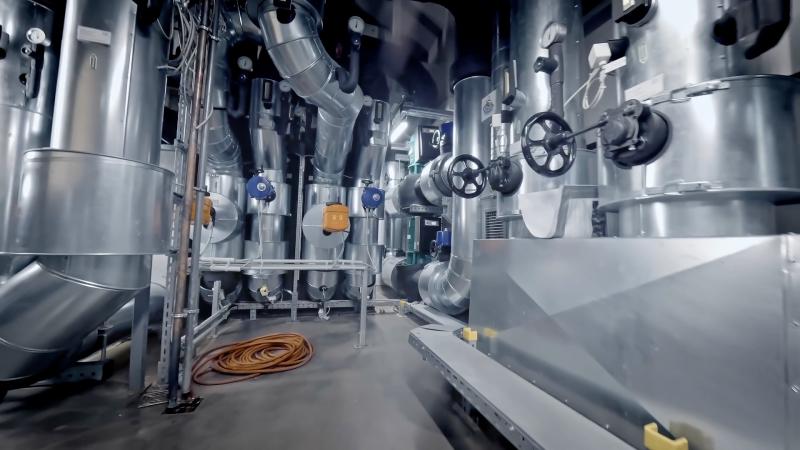 Technikraum mit großen Metallrohren, Ventilen und Steuerungselementen – Teil einer Kältekammer-Anlage.