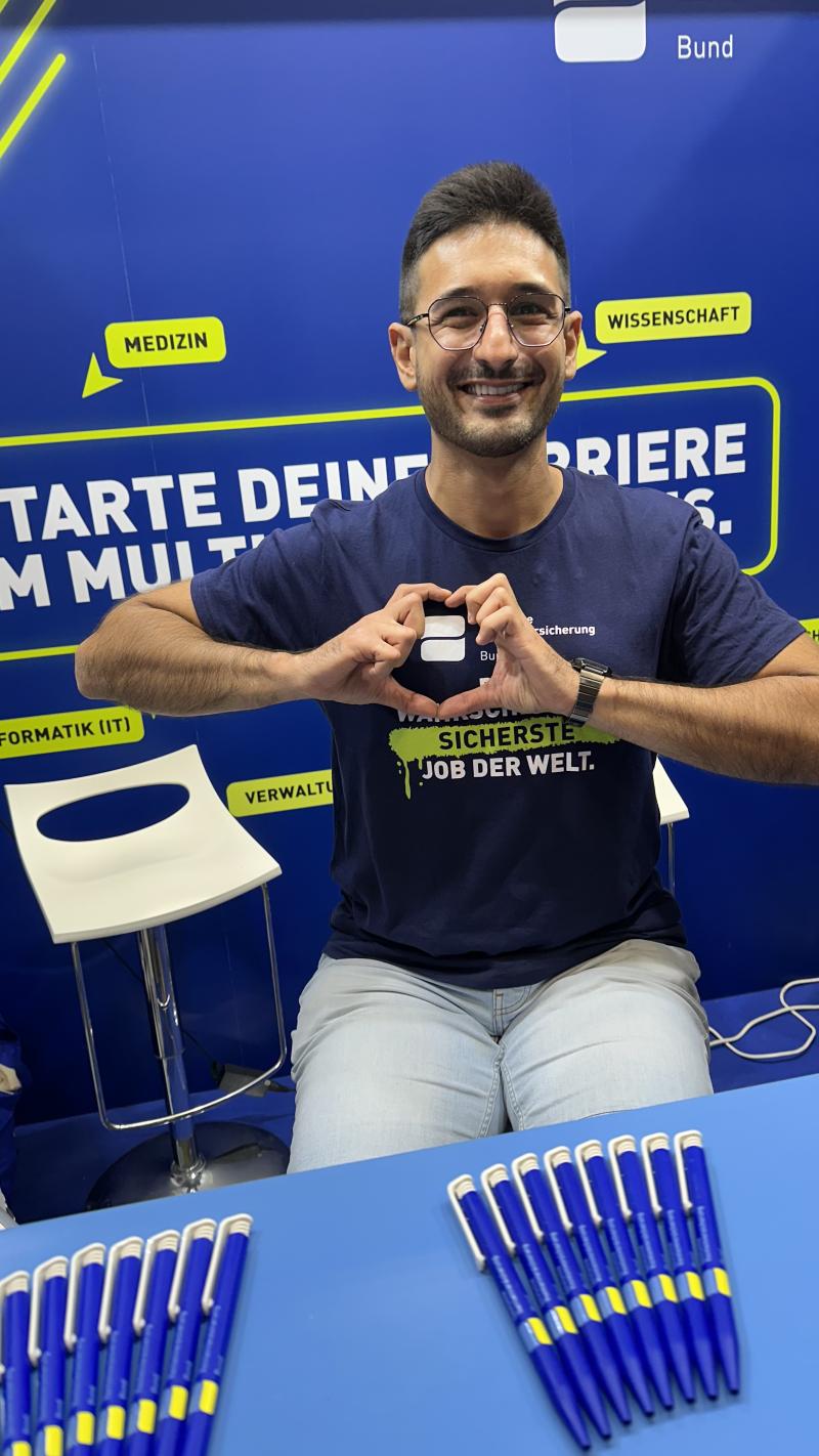 DRV Bund Mitarbeiter am Gamescom Stand, der mit den Händen ein Herz Zeichen formt.